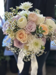Layered hand tied bouquet for the bride, in gorgeous summer pastels of faith, vuvuzela, peach dream with a touch of tanacetum and gypsophilia & oxypetalum for something blue.